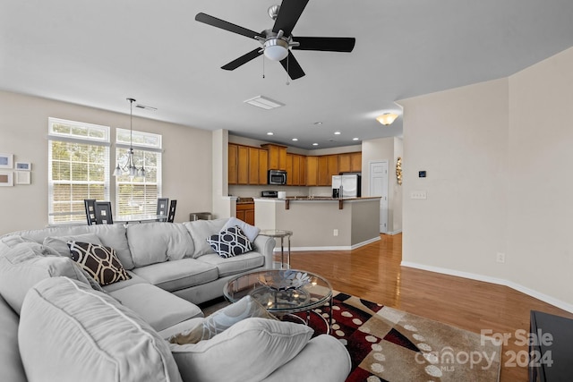 living room featuring ceiling fan with notable chandelier and wood-type flooring