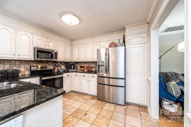 kitchen with crown molding, appliances with stainless steel finishes, dark stone countertops, backsplash, and white cabinets