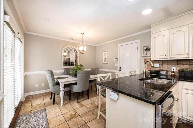 kitchen with sink, dark stone countertops, ornamental molding, pendant lighting, and backsplash