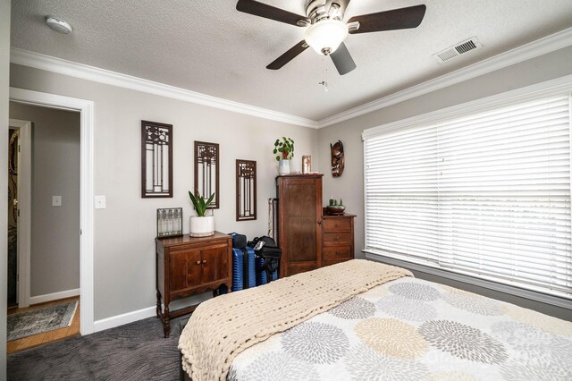 bedroom with dark colored carpet, crown molding, ceiling fan, and a textured ceiling