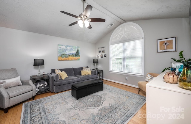 living room with hardwood / wood-style flooring, ceiling fan, and vaulted ceiling with beams