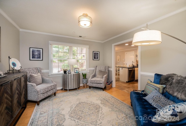 living room featuring ornamental molding, sink, and light hardwood / wood-style floors