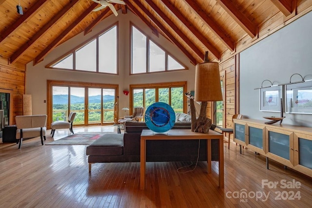 living room with high vaulted ceiling, light hardwood / wood-style flooring, wooden ceiling, wooden walls, and beam ceiling