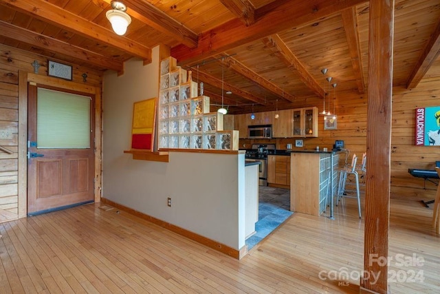 kitchen with appliances with stainless steel finishes, light hardwood / wood-style flooring, a kitchen breakfast bar, and decorative light fixtures