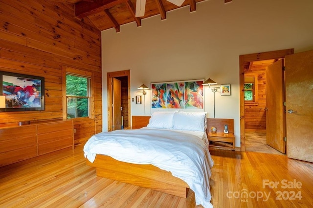 bedroom with wood ceiling, light hardwood / wood-style flooring, beamed ceiling, and wood walls