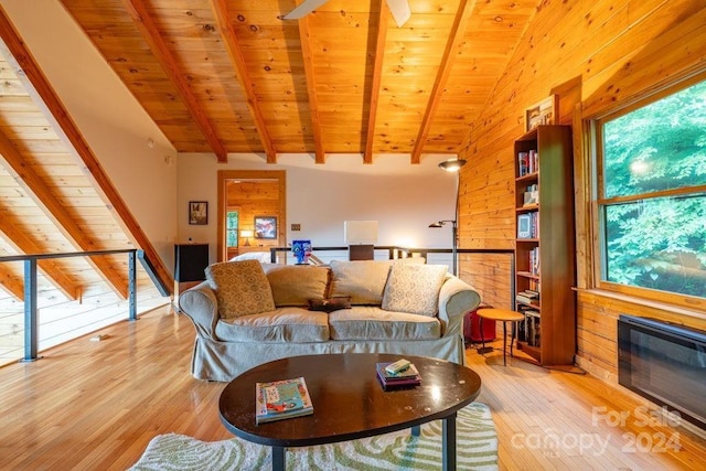 living room featuring vaulted ceiling with beams, light hardwood / wood-style floors, a healthy amount of sunlight, and wood walls