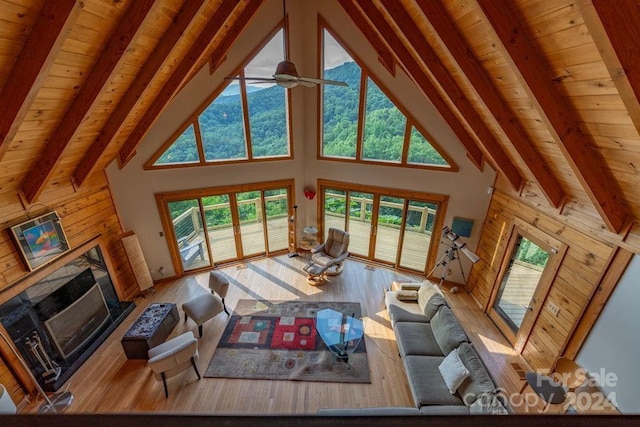 living room featuring light hardwood / wood-style flooring, wooden ceiling, wooden walls, and beamed ceiling