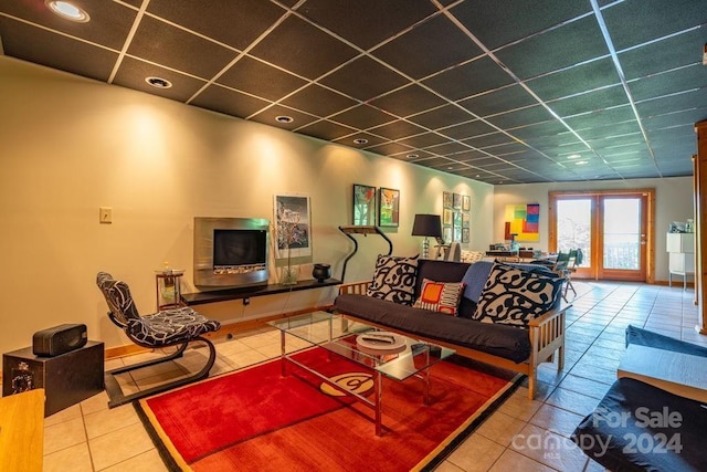 living room featuring tile patterned flooring and a paneled ceiling