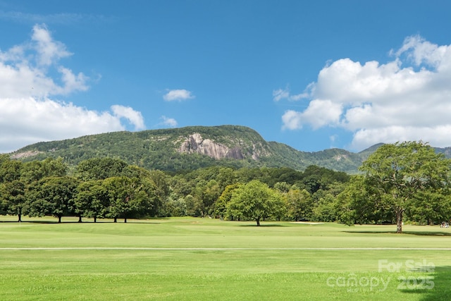 surrounding community with a mountain view and a lawn