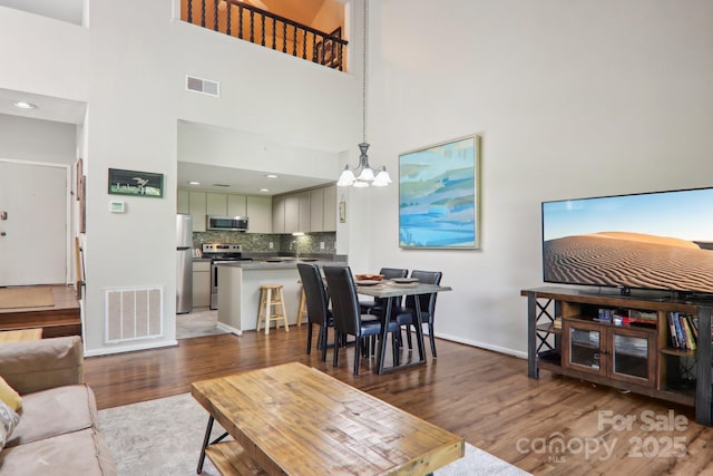 living room featuring a high ceiling, a notable chandelier, and dark hardwood / wood-style flooring