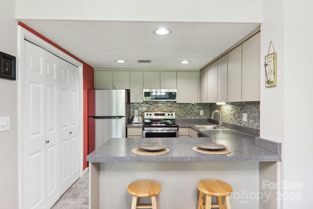 kitchen featuring appliances with stainless steel finishes, sink, a breakfast bar area, decorative backsplash, and kitchen peninsula