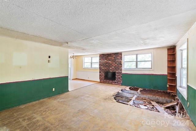 interior space featuring a brick fireplace, brick wall, and a textured ceiling