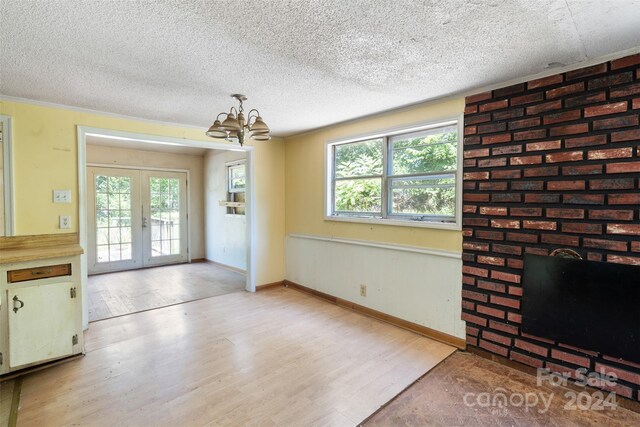 unfurnished dining area with a notable chandelier, a textured ceiling, and light hardwood / wood-style floors