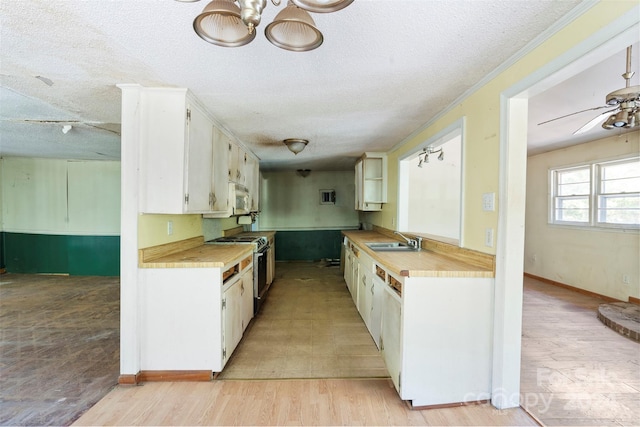 kitchen featuring a textured ceiling, white cabinets, light tile patterned flooring, white appliances, and sink