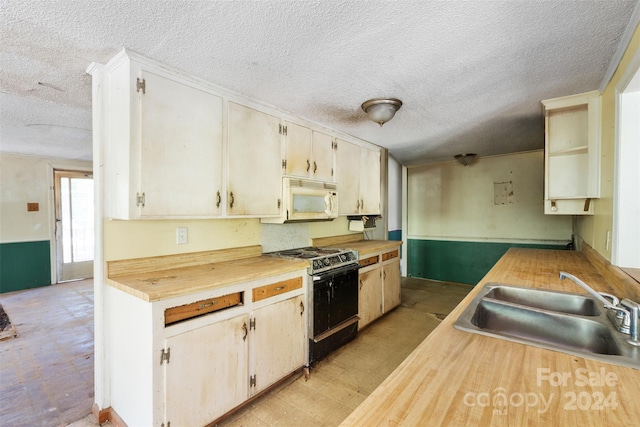 kitchen with sink, gas stove, and a textured ceiling