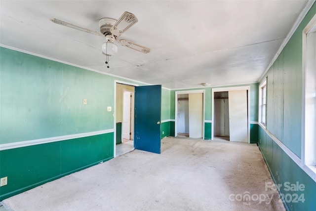 unfurnished bedroom featuring ceiling fan and multiple closets