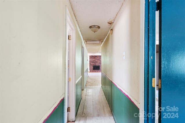 hallway featuring light wood-type flooring and a textured ceiling