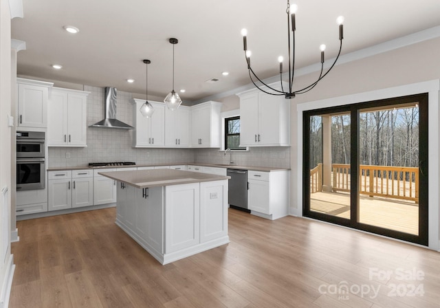 kitchen with white cabinetry, appliances with stainless steel finishes, wall chimney exhaust hood, and a center island