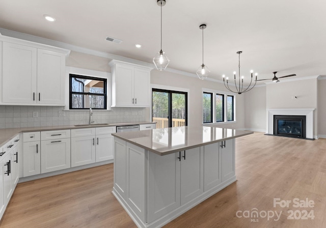 kitchen with sink, decorative light fixtures, a center island, and white cabinets