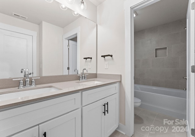 full bathroom featuring tile patterned flooring, vanity, tiled shower / bath, and toilet