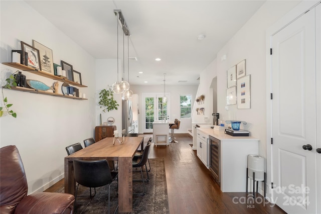 dining area featuring beverage cooler and dark wood-type flooring