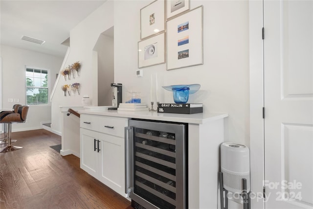 bar with sink, white cabinetry, beverage cooler, and dark wood-type flooring