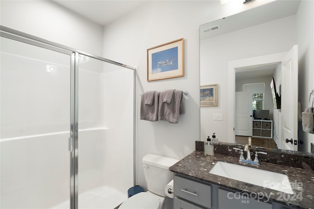 bathroom featuring a shower with shower door, vanity, and toilet