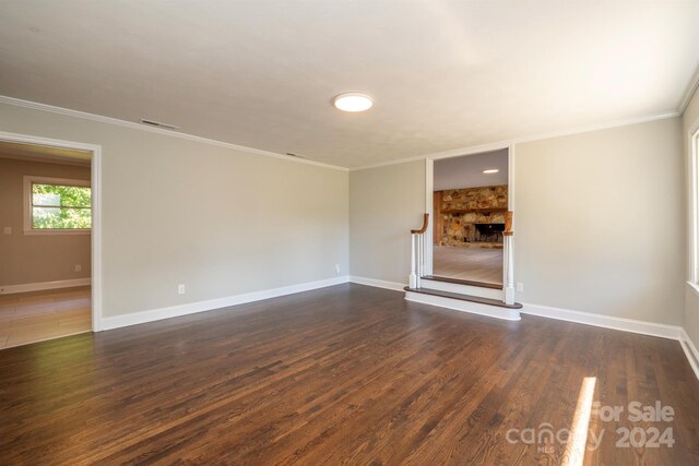 interior space with dark wood-type flooring, a fireplace, and crown molding