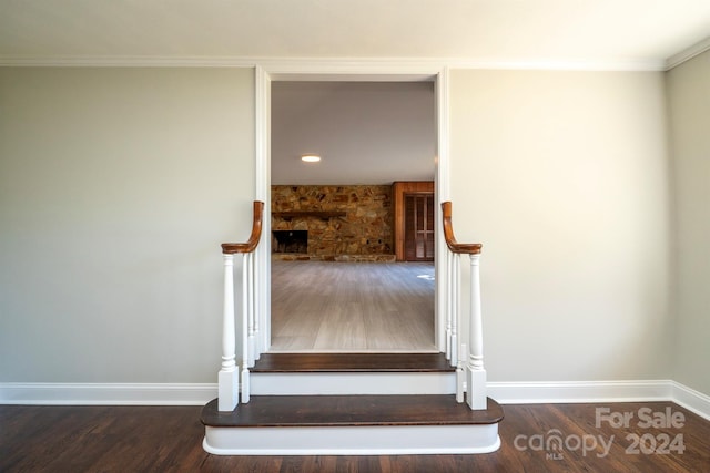 stairway with wood-type flooring and crown molding