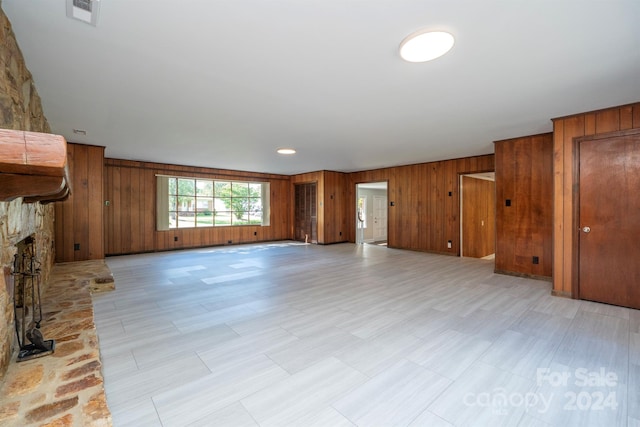 unfurnished living room featuring wooden walls and a fireplace