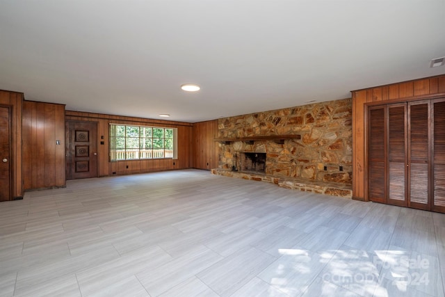 unfurnished living room with a fireplace and wood walls