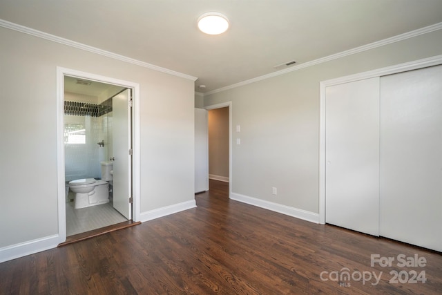 unfurnished bedroom featuring crown molding, dark hardwood / wood-style floors, ensuite bathroom, and a closet