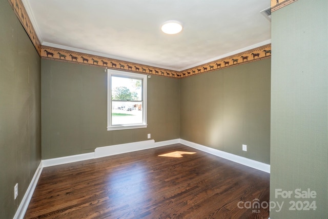 empty room with dark hardwood / wood-style floors and crown molding