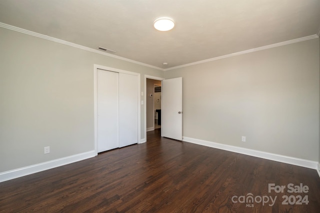 unfurnished bedroom with a closet, crown molding, and dark hardwood / wood-style flooring