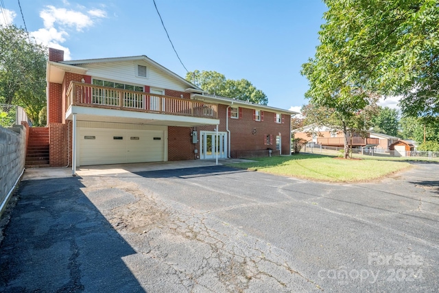 view of front of house with a front yard, a garage, and a balcony