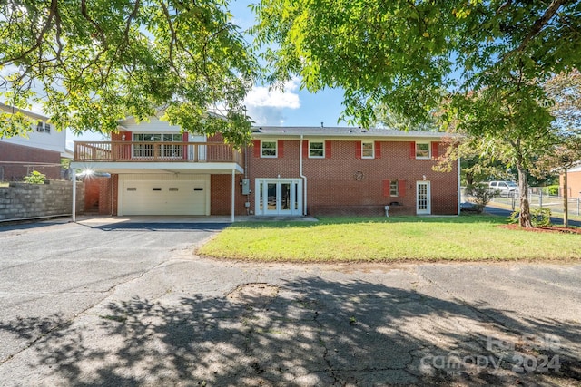 view of front facade featuring a balcony, a front lawn, french doors, and a garage