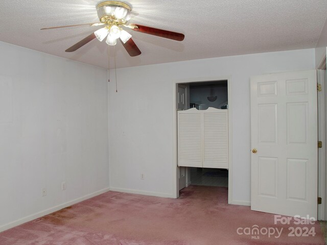 unfurnished bedroom featuring a textured ceiling, carpet, a closet, and ceiling fan