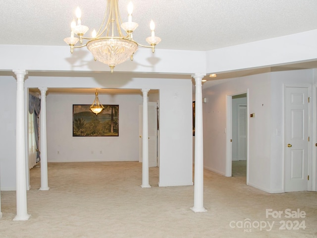 unfurnished living room featuring decorative columns, a textured ceiling, light colored carpet, and an inviting chandelier