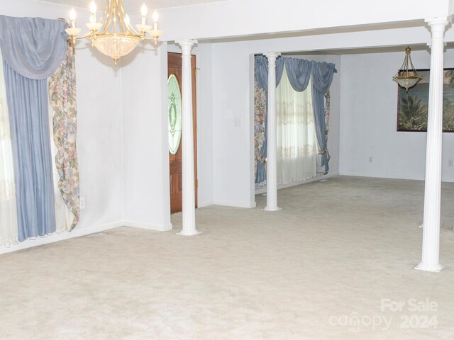 unfurnished room with decorative columns, an inviting chandelier, and carpet floors