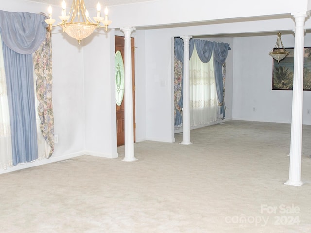 carpeted empty room featuring decorative columns and a notable chandelier