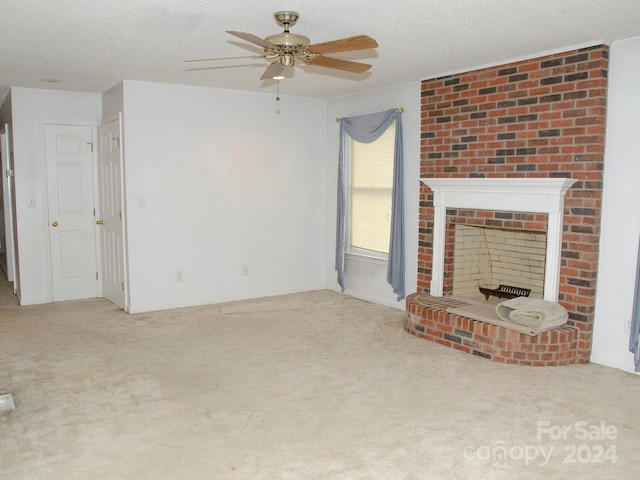 unfurnished living room with ceiling fan, a fireplace, a textured ceiling, and light colored carpet