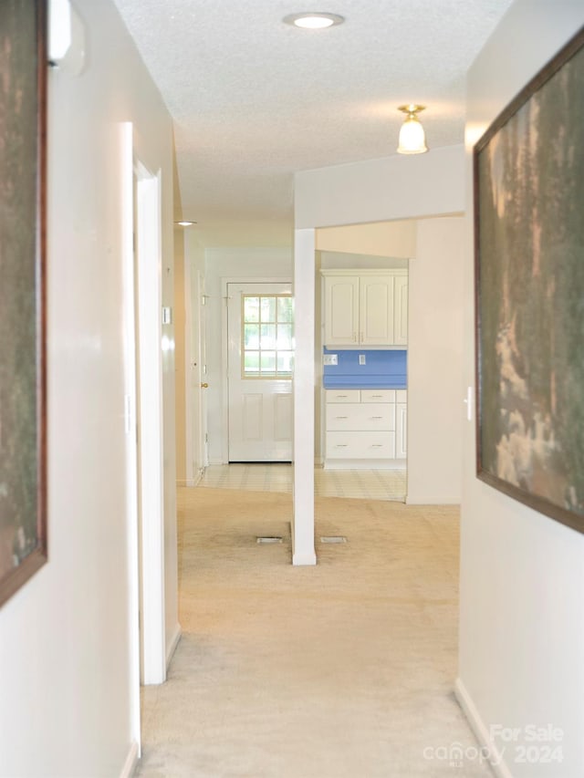 hallway featuring light tile patterned flooring and a textured ceiling