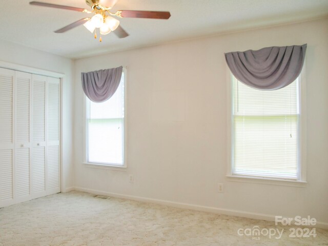 unfurnished bedroom with carpet, a closet, and ceiling fan