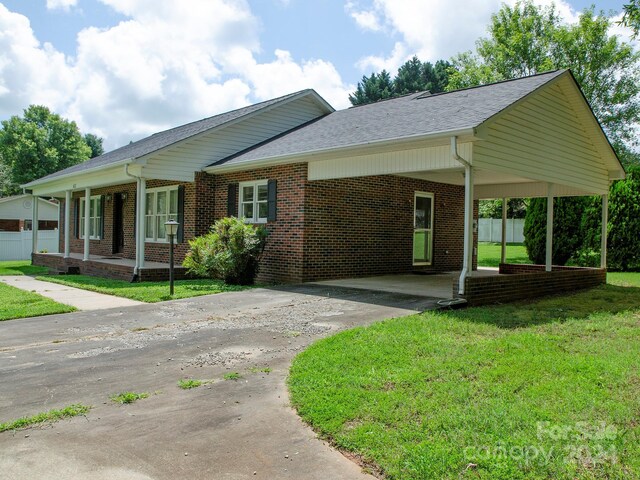 ranch-style house with a carport and a front lawn