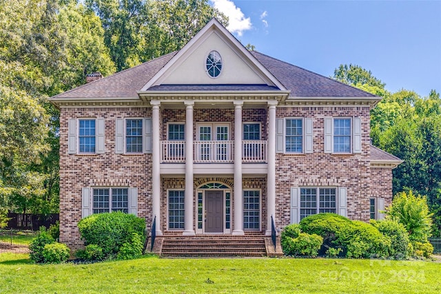 greek revival house with a front lawn and a balcony