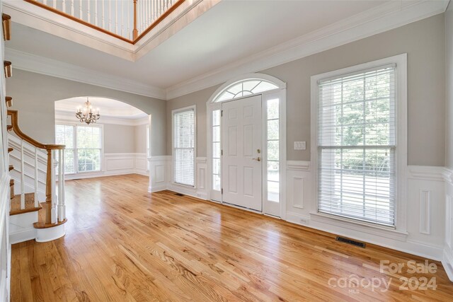 foyer featuring light wood-type flooring, ornamental molding, and a chandelier