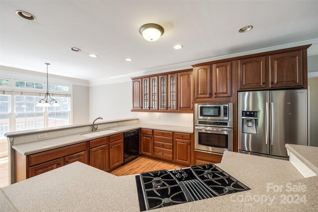 kitchen featuring hanging light fixtures, sink, black appliances, light hardwood / wood-style flooring, and kitchen peninsula