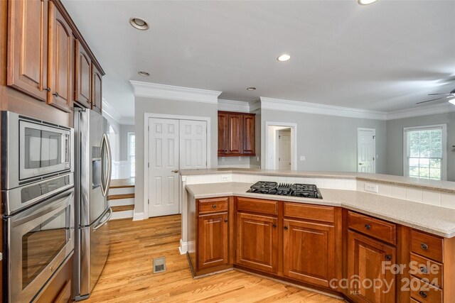 kitchen featuring crown molding, appliances with stainless steel finishes, ceiling fan, light hardwood / wood-style flooring, and kitchen peninsula