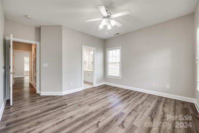 unfurnished bedroom with connected bathroom, wood-type flooring, and ceiling fan