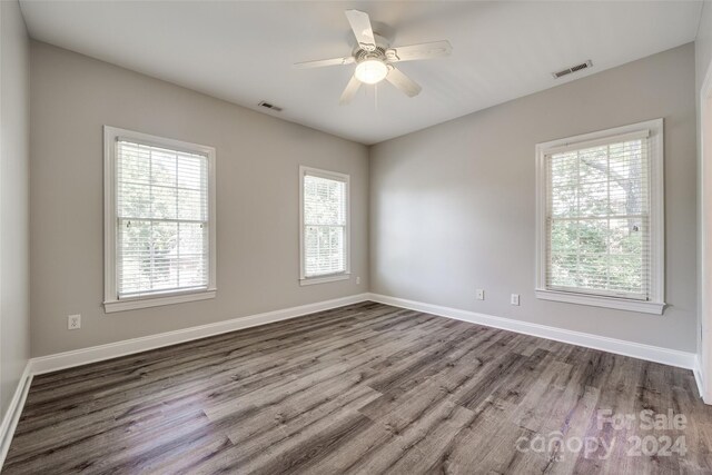 empty room with ceiling fan, plenty of natural light, and hardwood / wood-style flooring